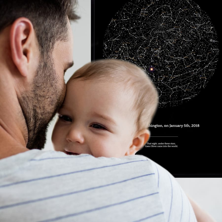Un giovane papà con un bambino davanti alla mappa stellare che commemora la nascita del bambino